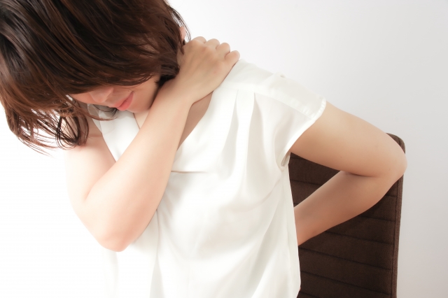 肩と腰の痛みに苦しむ女性